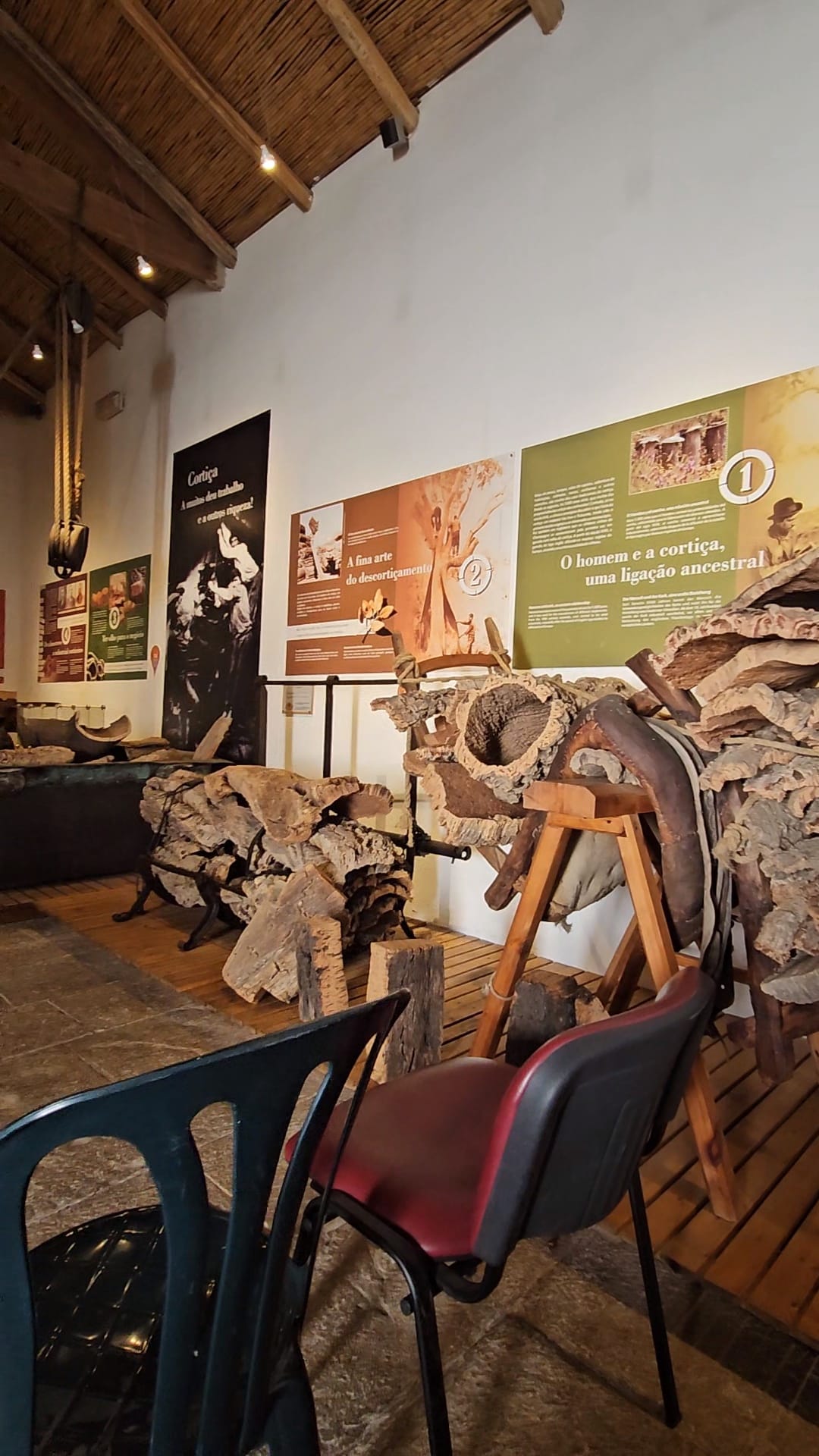 Interior of a cork museum in Portugal displaying large rough cut pieces of harvested cork bark with informational panels on the walls