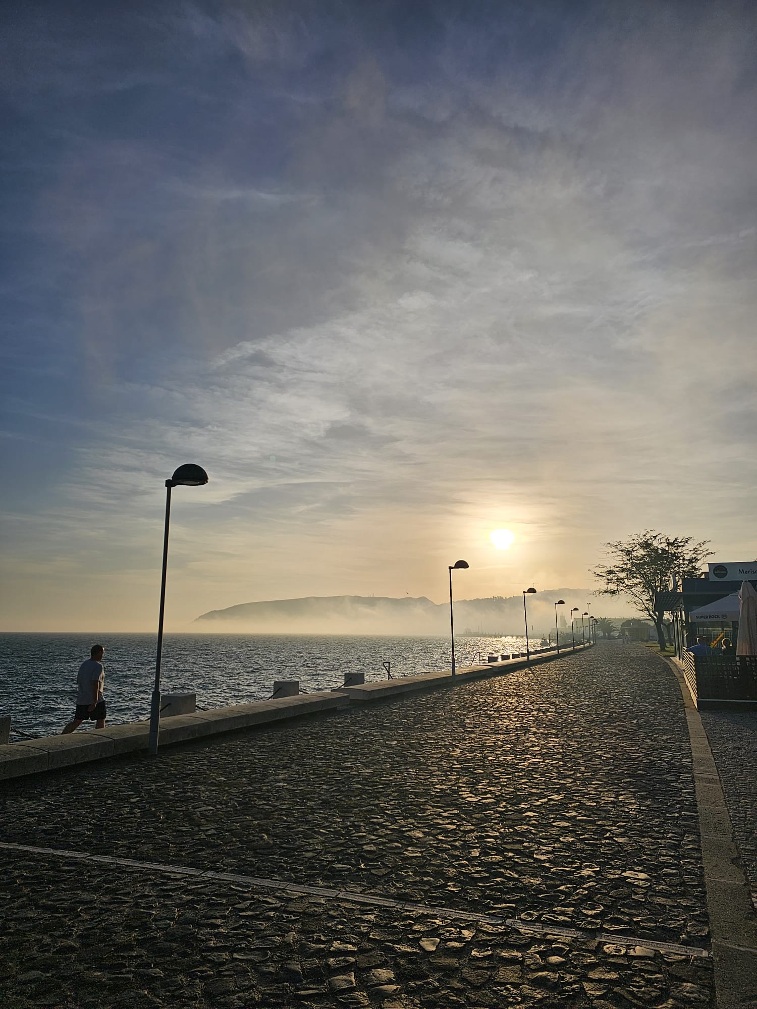 Waterfront walkway at sunset with heavy fog and a mountain in the background