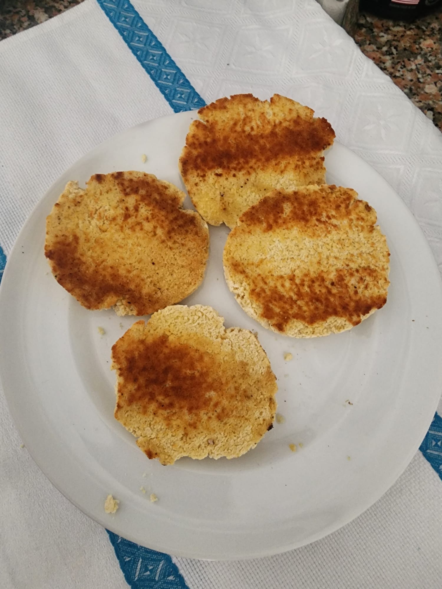 Four gluten-free biscuits sliced open and toasted golden brown on a white plate