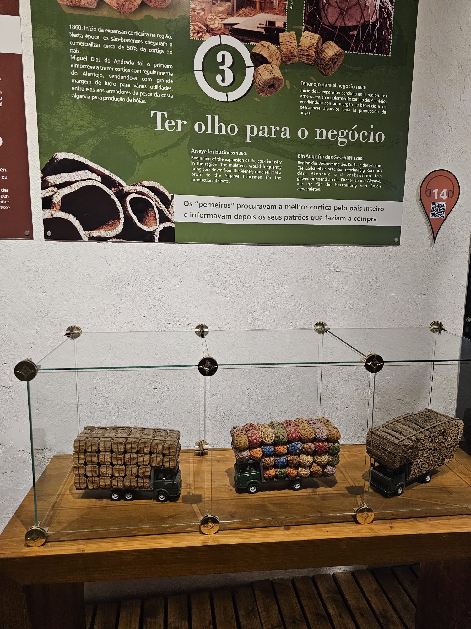 Museum display panel titled "Ter olho para o negócio" showing miniature model trucks transporting bales of cork in Portugal
