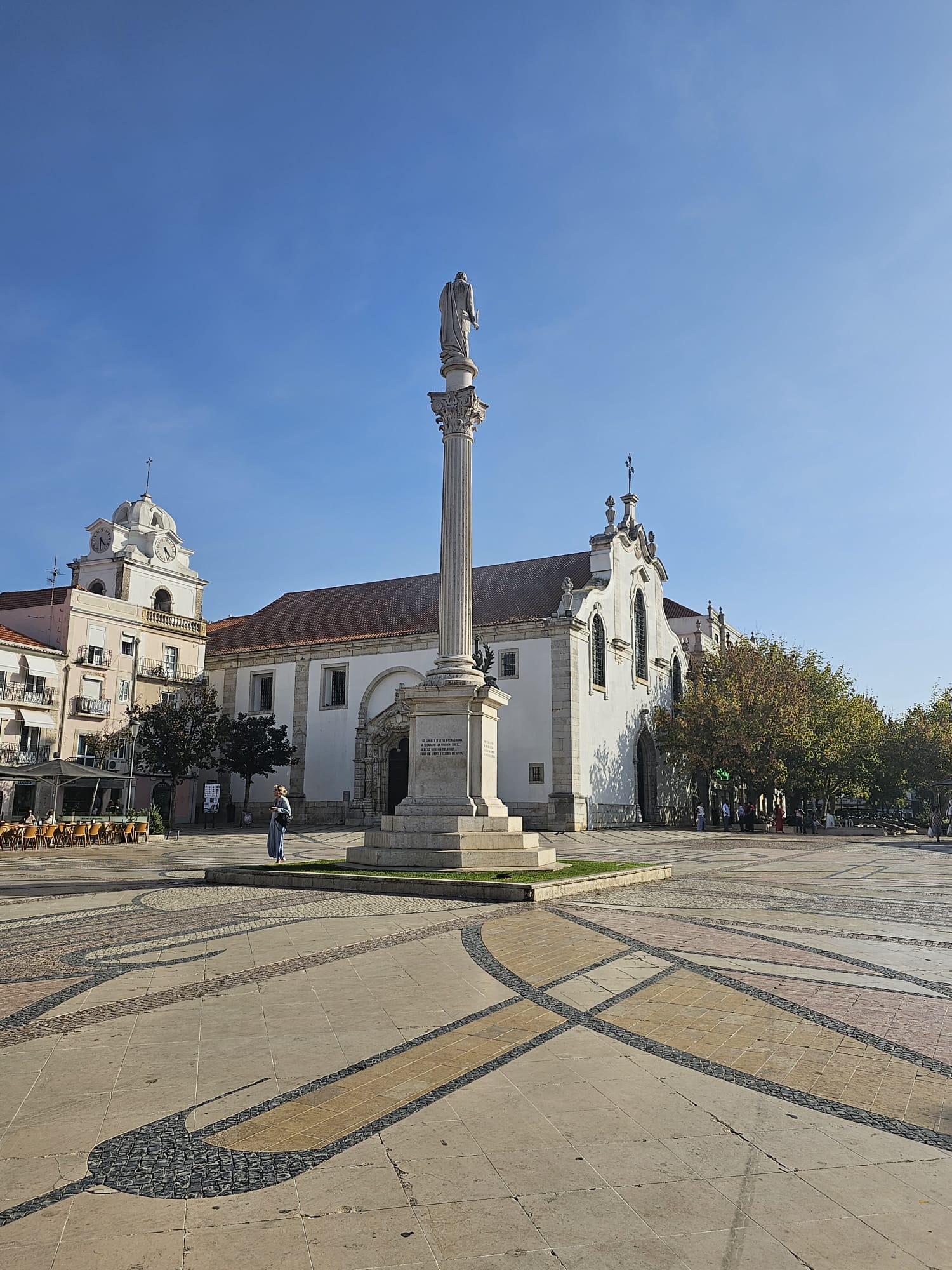A monument in the town center with a Portuguese church in the background