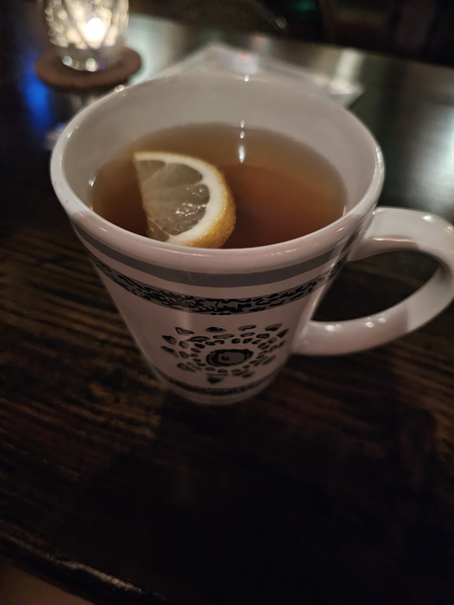 A blue and white decorated cup filled with hot tea and a slice of lemon