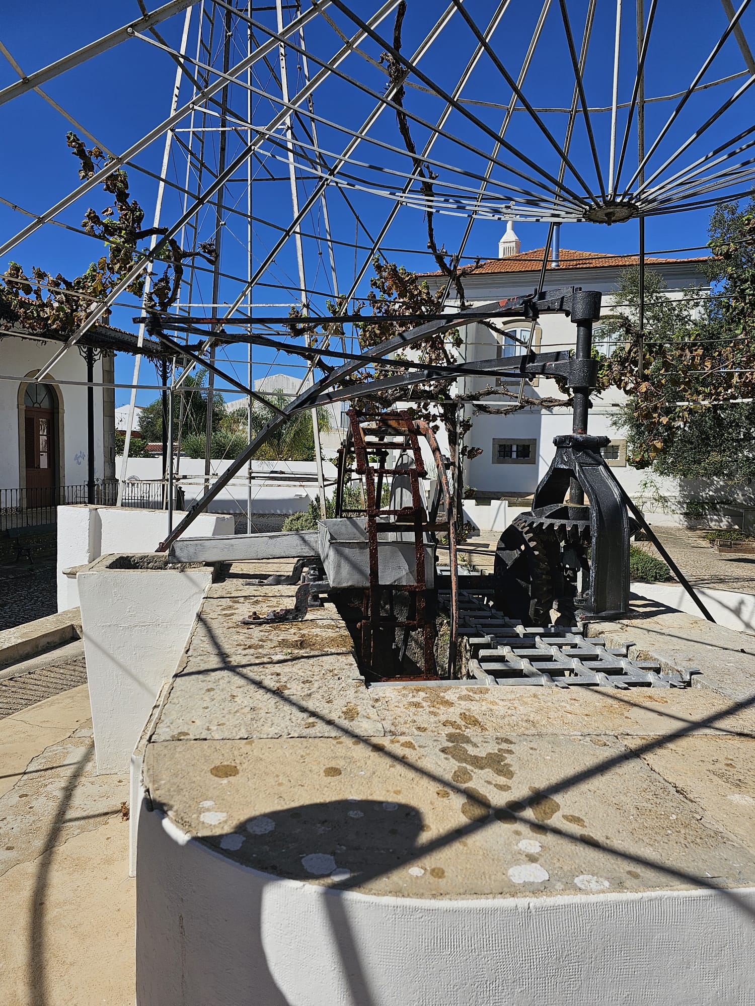 Exterior view of an old operational stone well with iron pulley mechanism at a heritage museum in Portugal