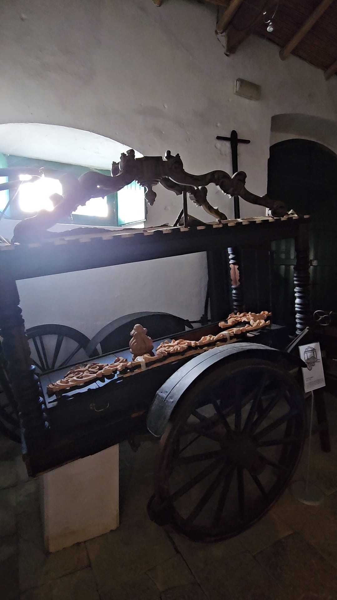 Ornate black antique wooden hearse with decorative carvings on display at a heritage museum in Portugal