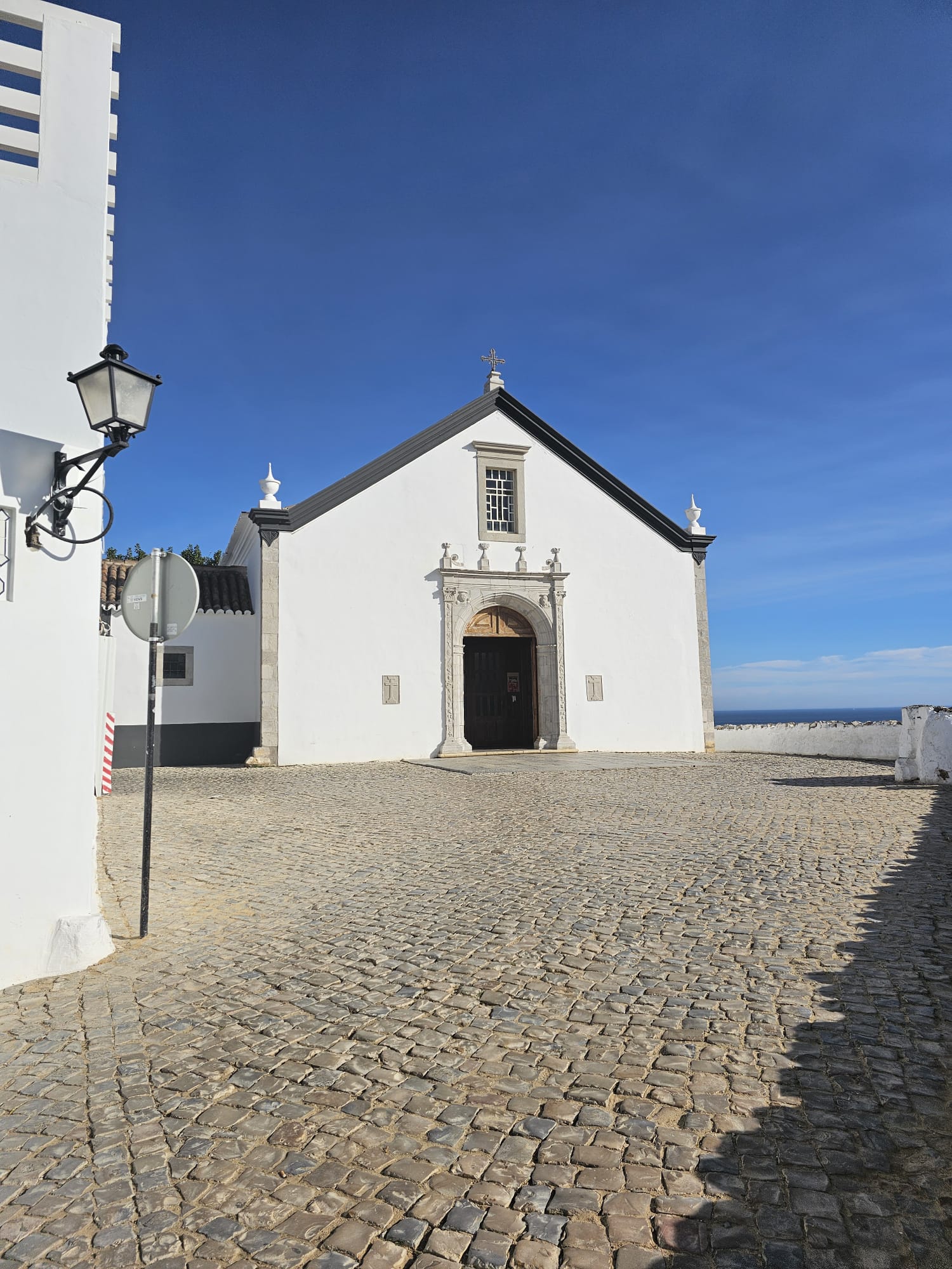 White facade of the historic church of Cacela Velha against a bright blue sky in Portugal