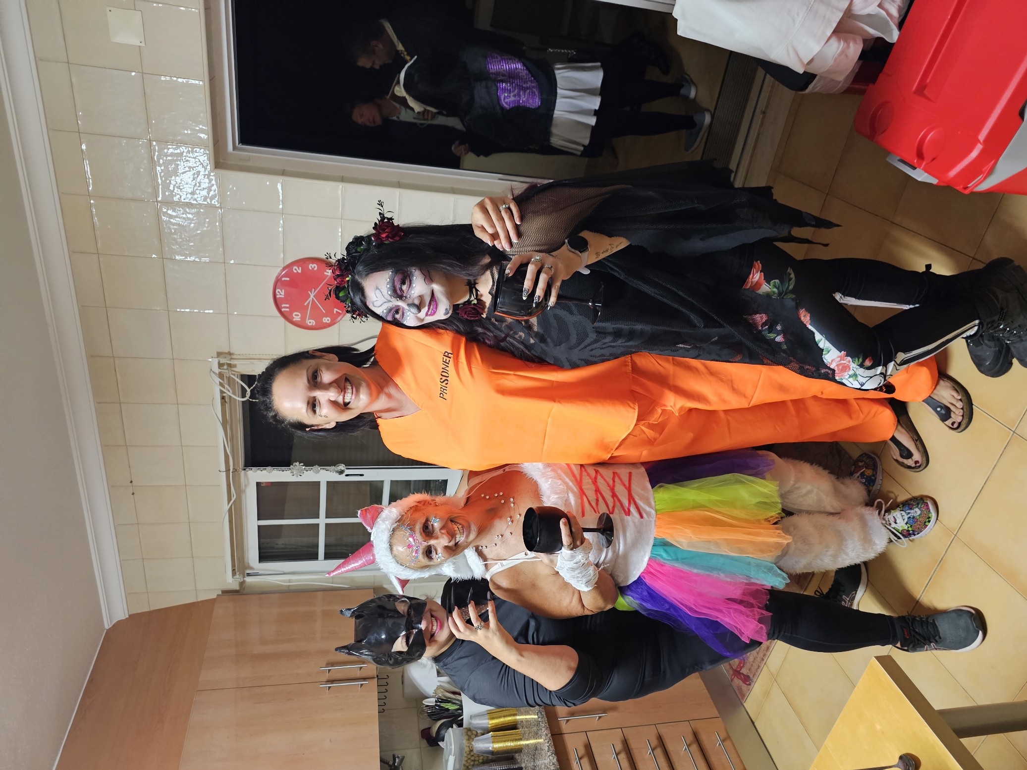 Group of friends in colorful Halloween costumes including a prisoner outfit and black witch at a Halloween party in Portugal