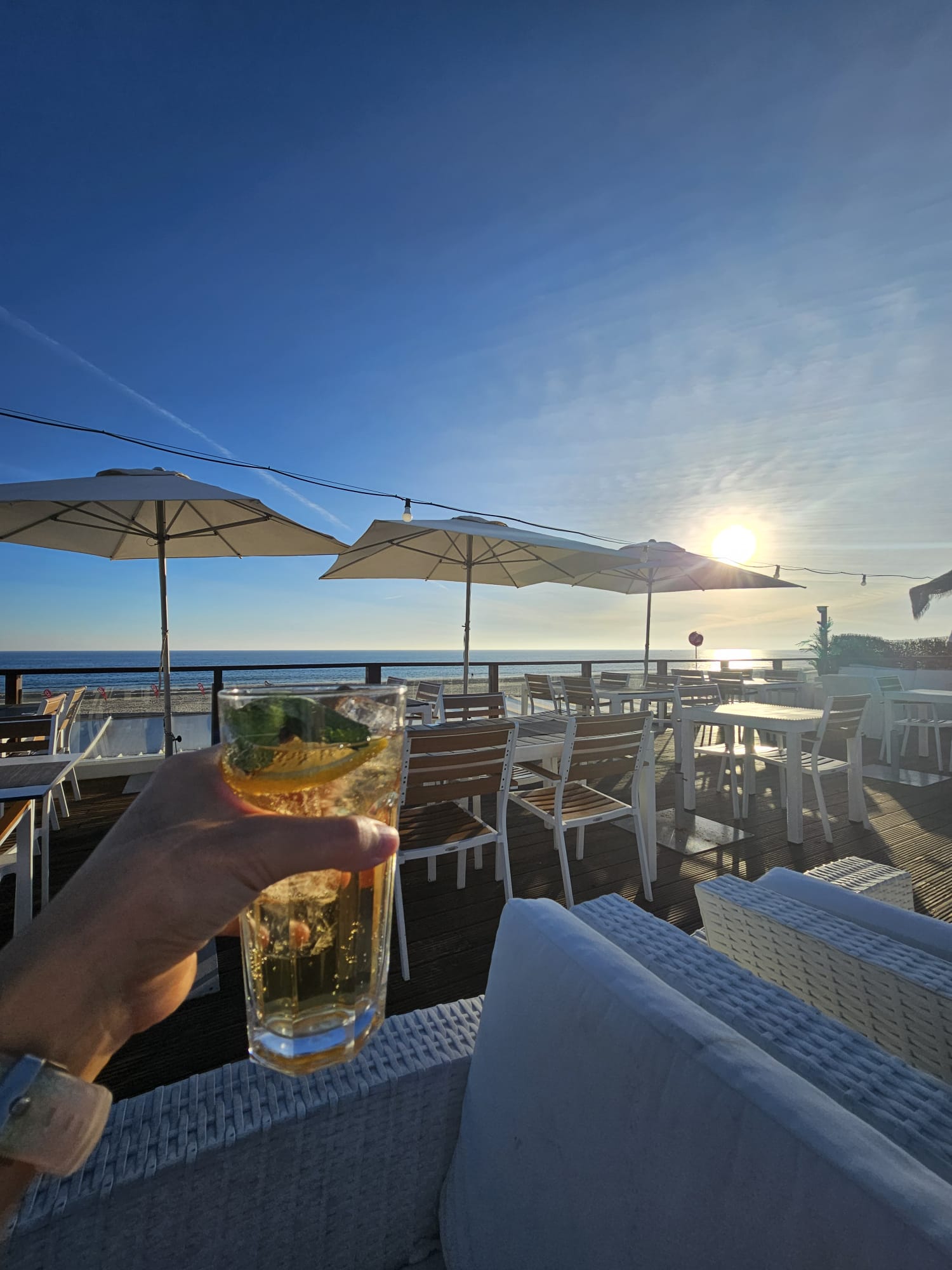Cocktail held up at sunset on the rooftop terrace of Marsalgado restaurant overlooking the ocean in Monte Gordo Portugal