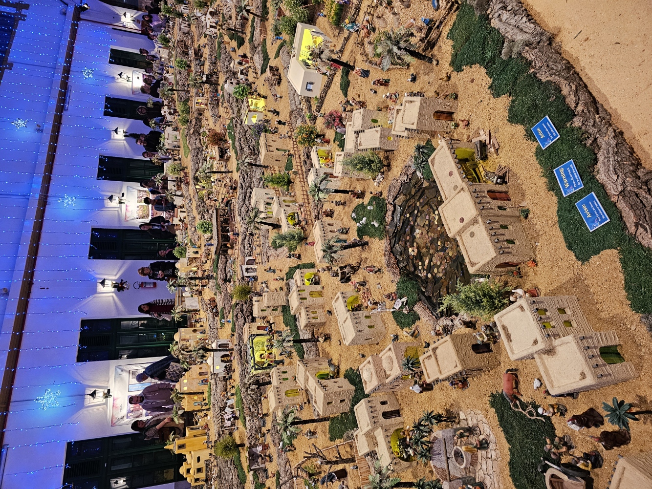 Wide view of the sprawling handcrafted nativity scene with miniature figures and palm trees