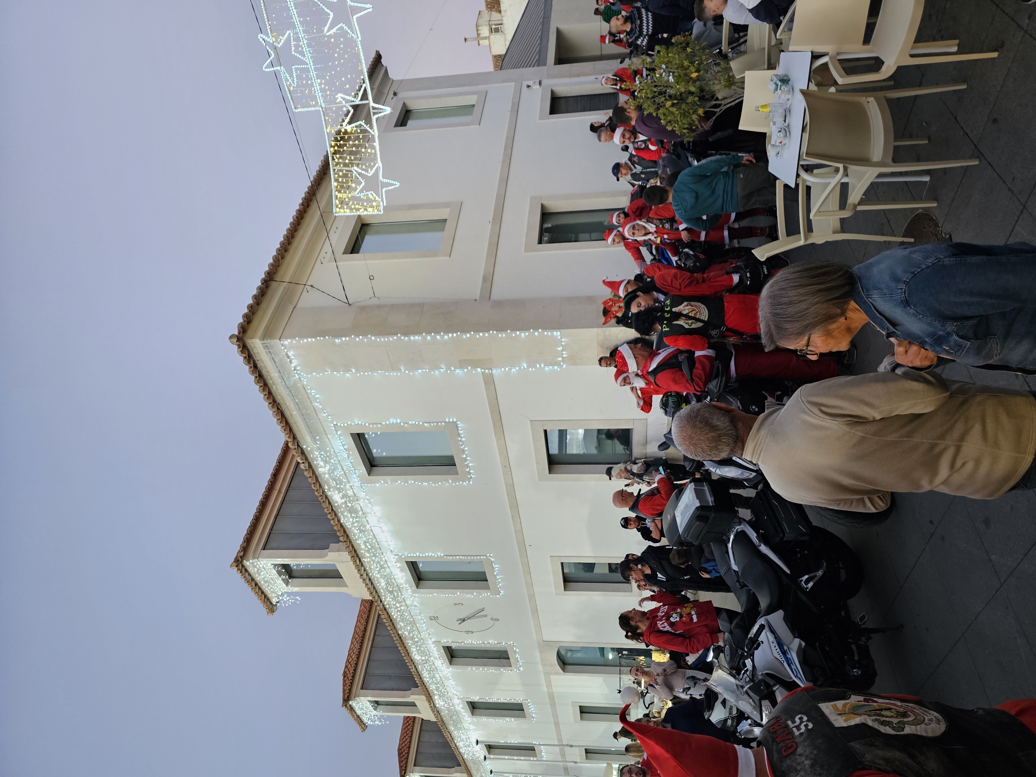 Group of motorcycle riders dressed in Santa Claus costumes gathered outside a building decorated with Christmas lights in Vila Real de Santo António Portugal