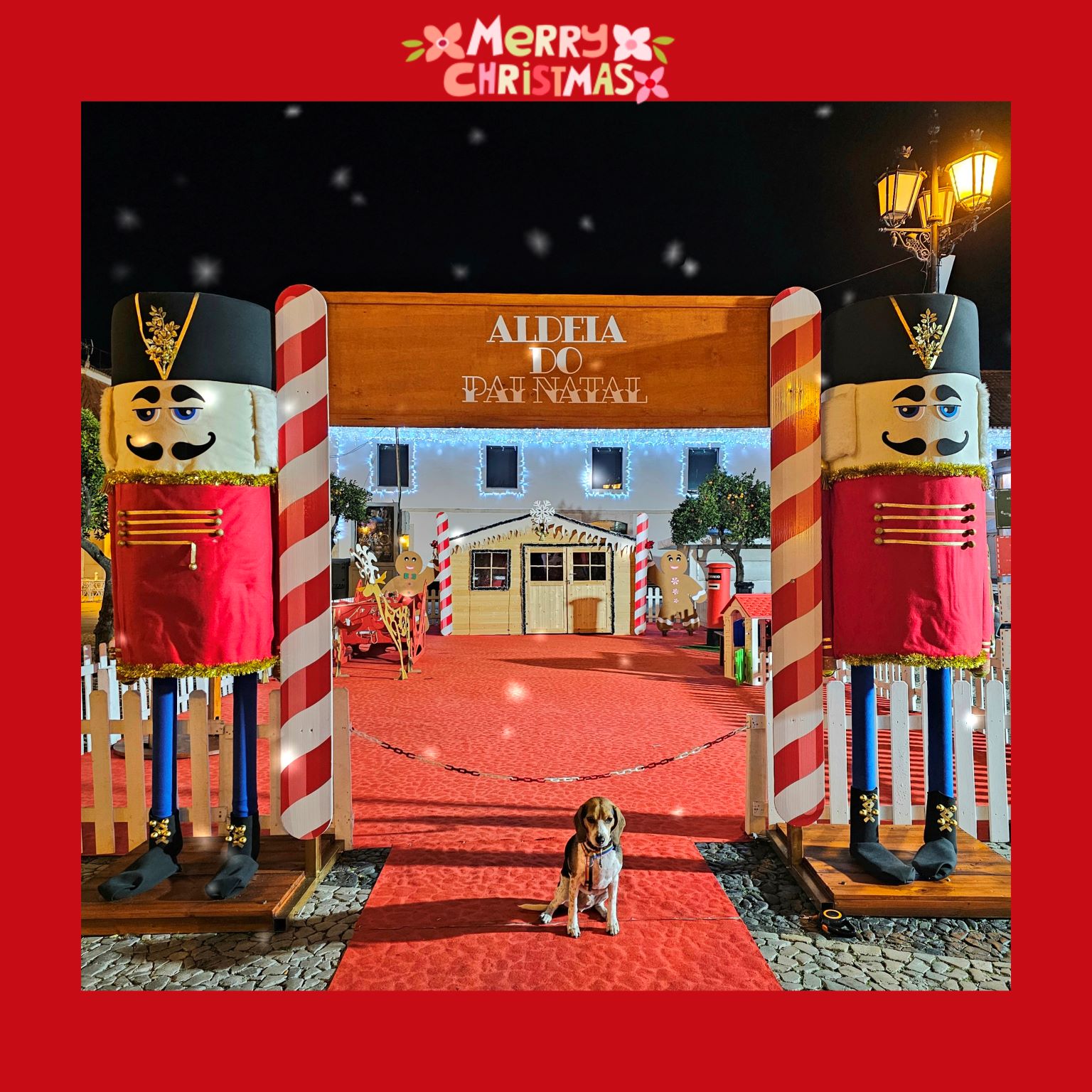 Beagle dog sitting at the entrance of the Aldeia do Pai Natal Christmas Village in Vila Real de Santo António Portugal, flanked by giant nutcracker decorations