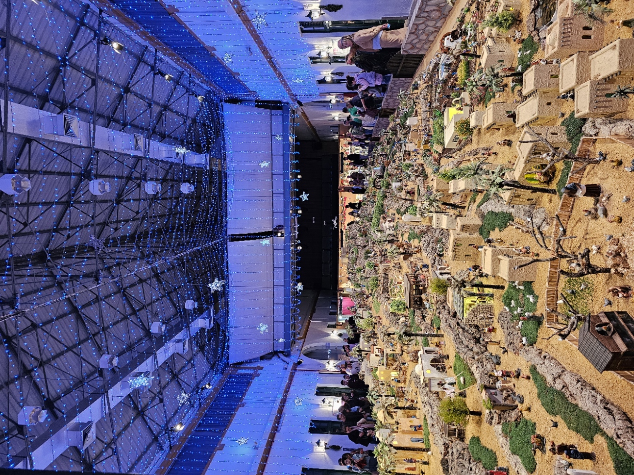 Aerial view of Portugal's largest nativity scene displayed under blue lit ceiling at Vila Real de Santo António, featuring an elaborately detailed miniature ancient town