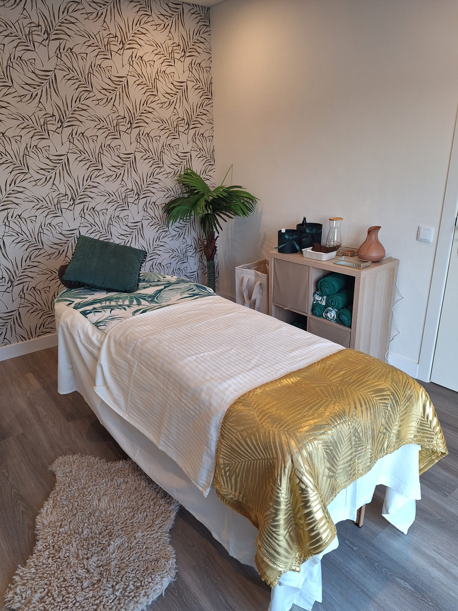 Serene massage treatment room with botanical print wallpaper, white and gold linens and natural decor at Human Movement Studio in Portugal