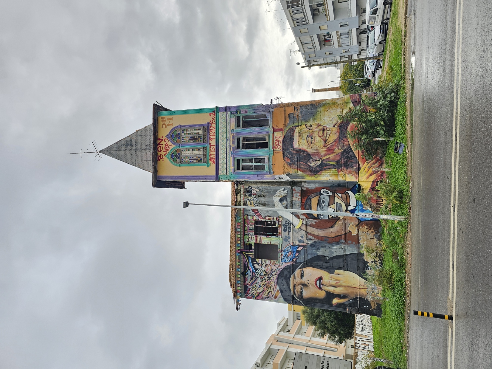 Tall abandoned building with large portrait street art murals painted on its facade in Olhão Portugal