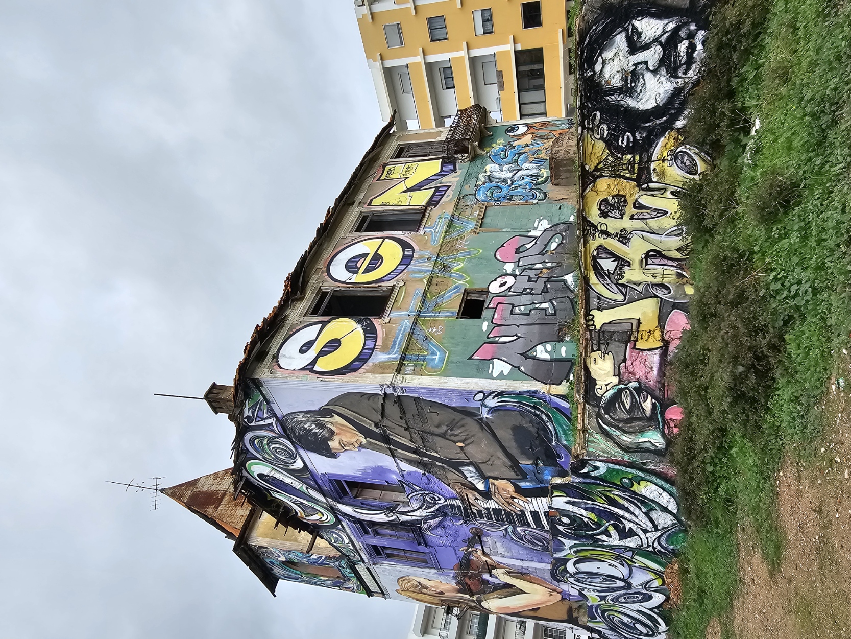 Wide view of the graffiti covered abandoned church with large scale street art murals in Olhão Portugal