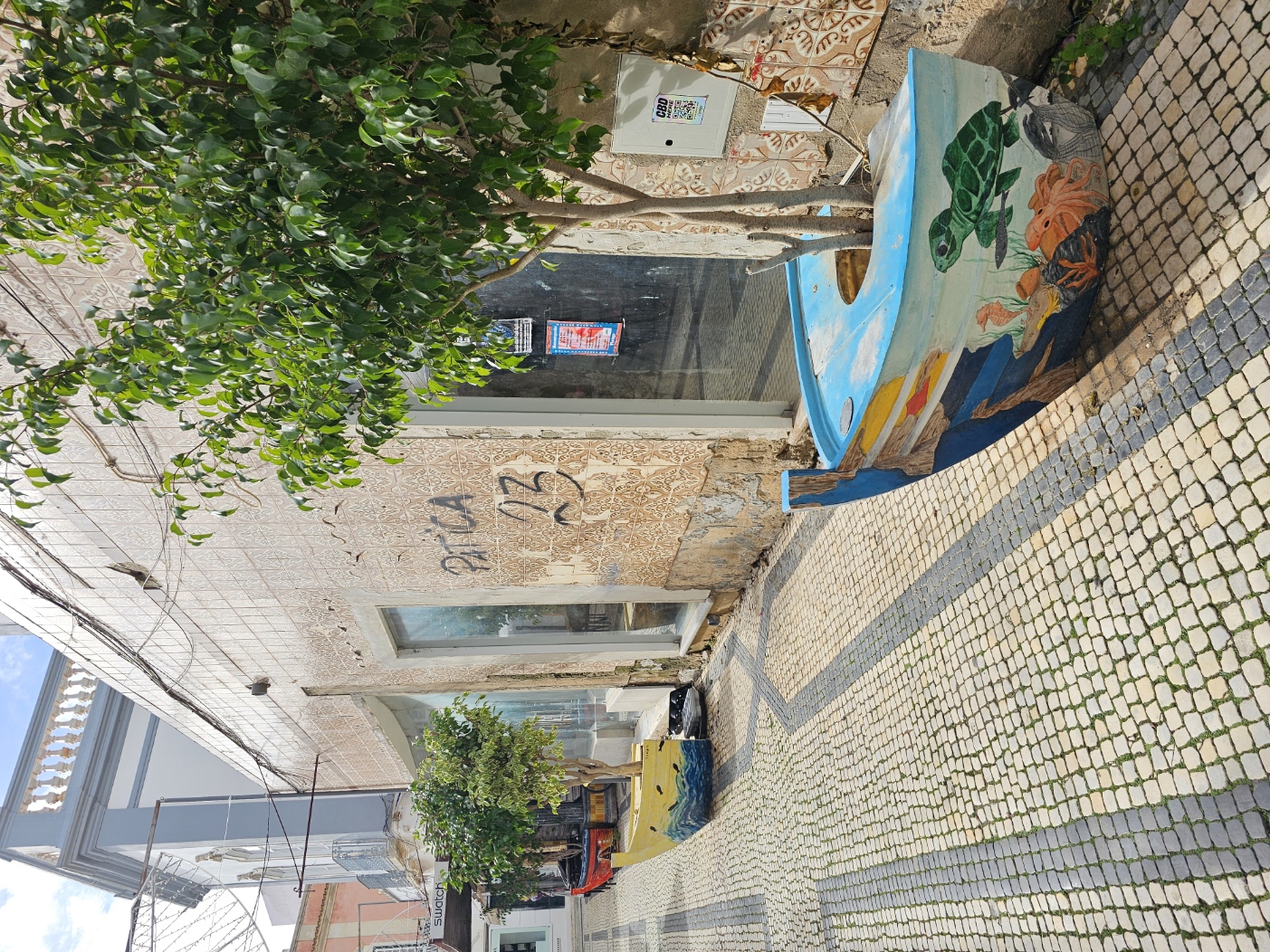 Narrow alley in Olhão with a colorful painted boat propped against a wall