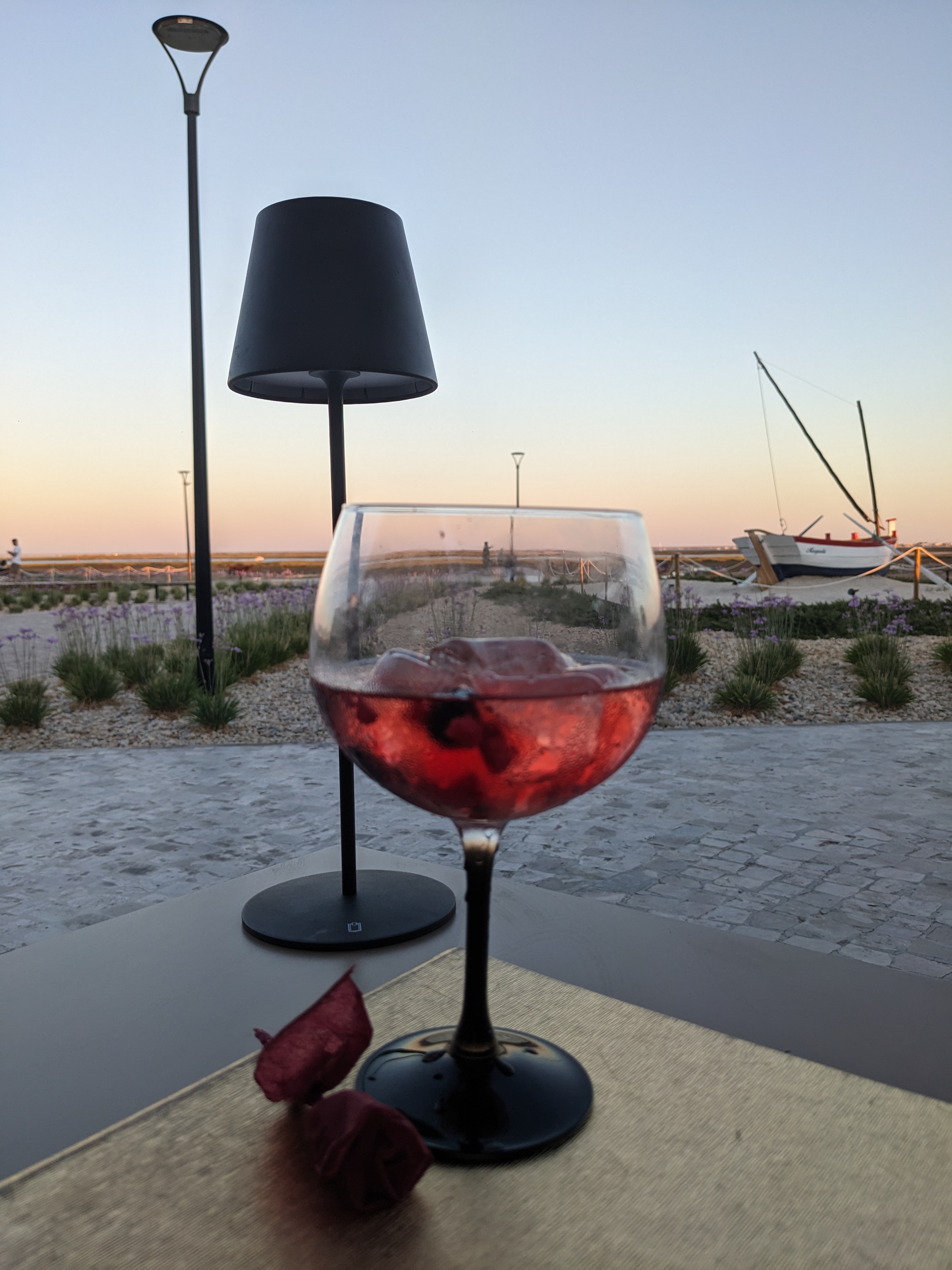 Glass of sangria on an outdoor table at sunset at Marina Ria Olhão with the Ria Formosa lagoon in the background