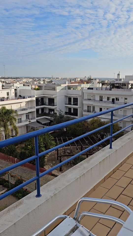 Rooftop terrace view overlooking the white rooftops and buildings of Tavira Portugal with blue railings in the foreground