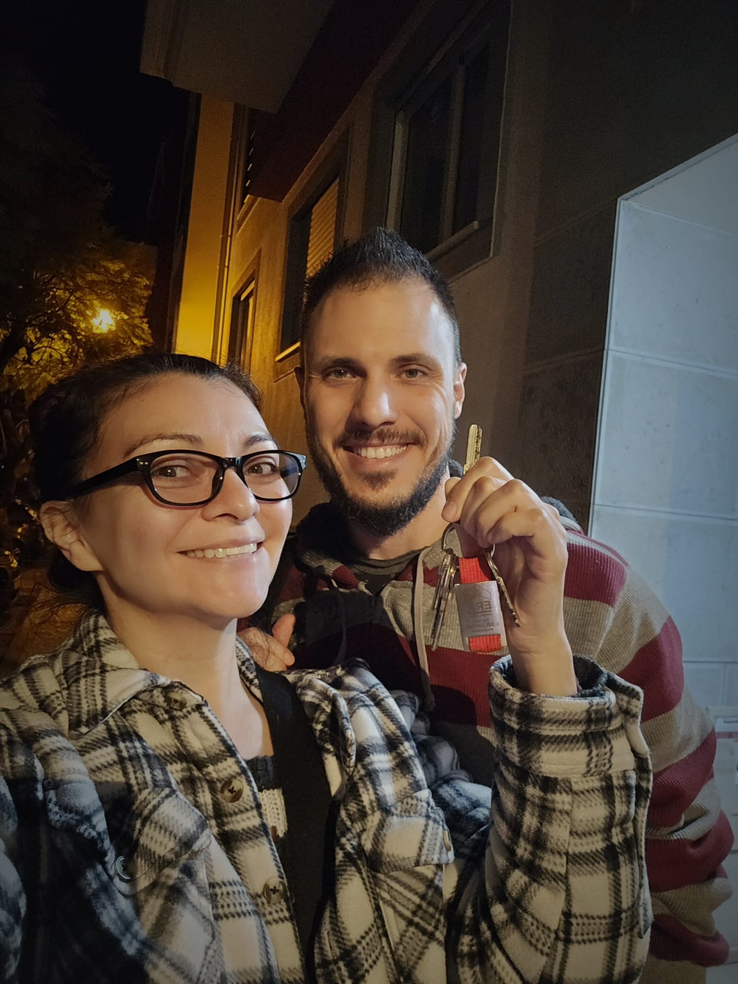 Couple smiling and holding up the keys to their new apartment in Portugal after completing the purchase signing