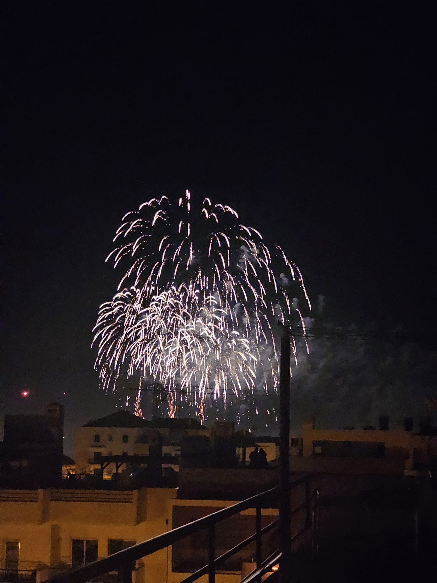 New Year's Eve fireworks lighting up the night sky over rooftops in Portugal, viewed from a private rooftop patio