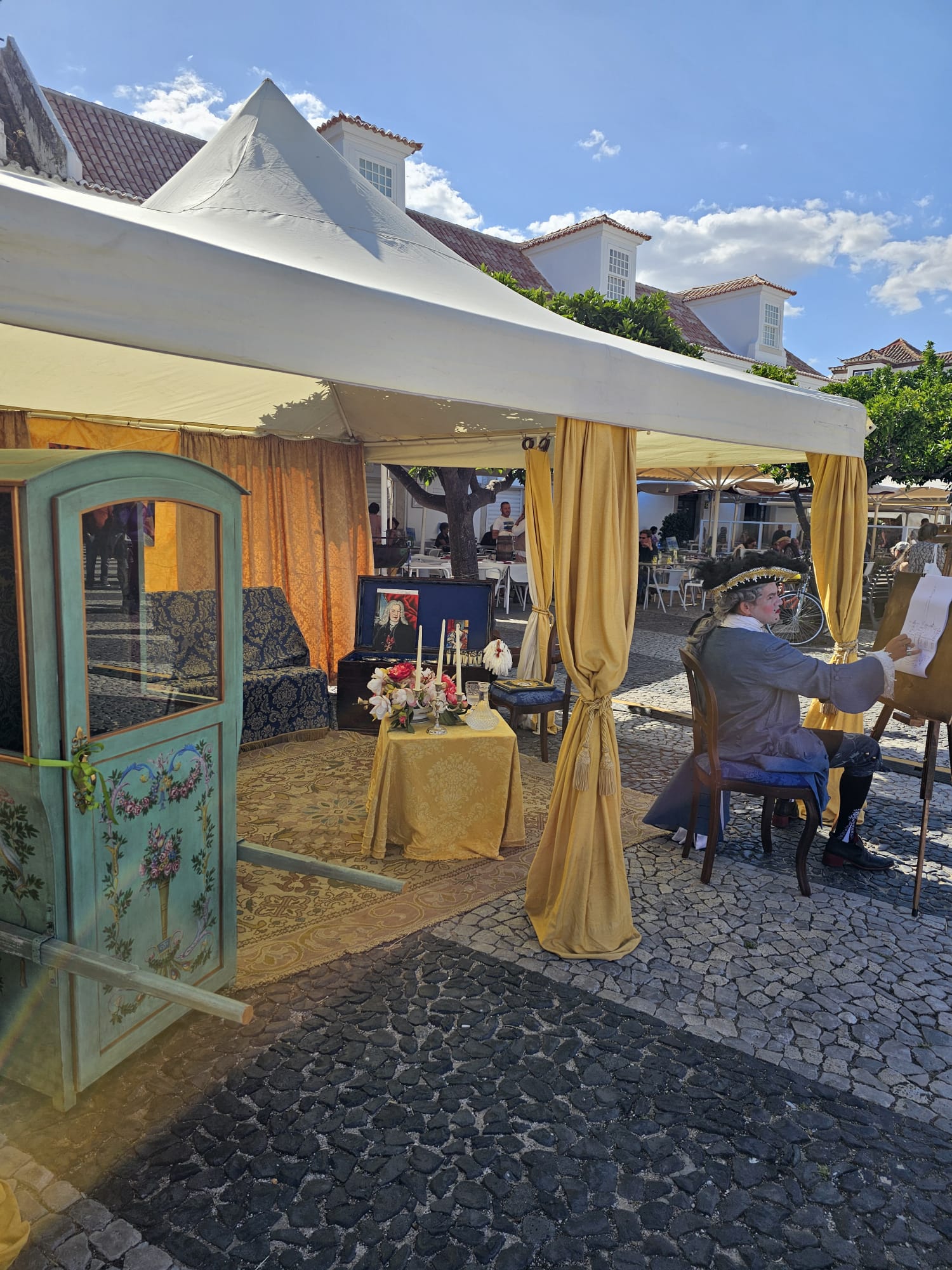 Artist sketching live portraits at an outdoor booth during a historical festival in Portugal