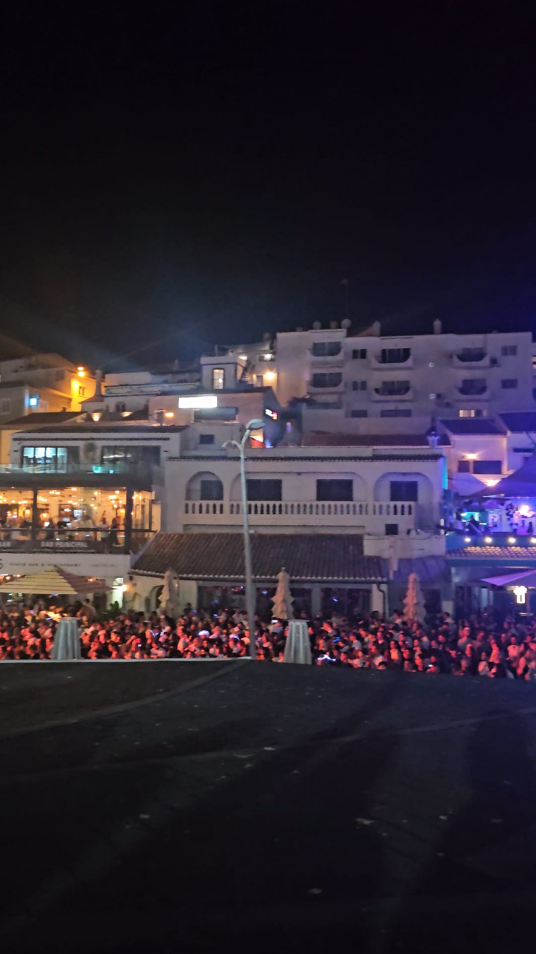 Packed beachfront crowds at night during Carvoeiro Black and White Night in the Algarve