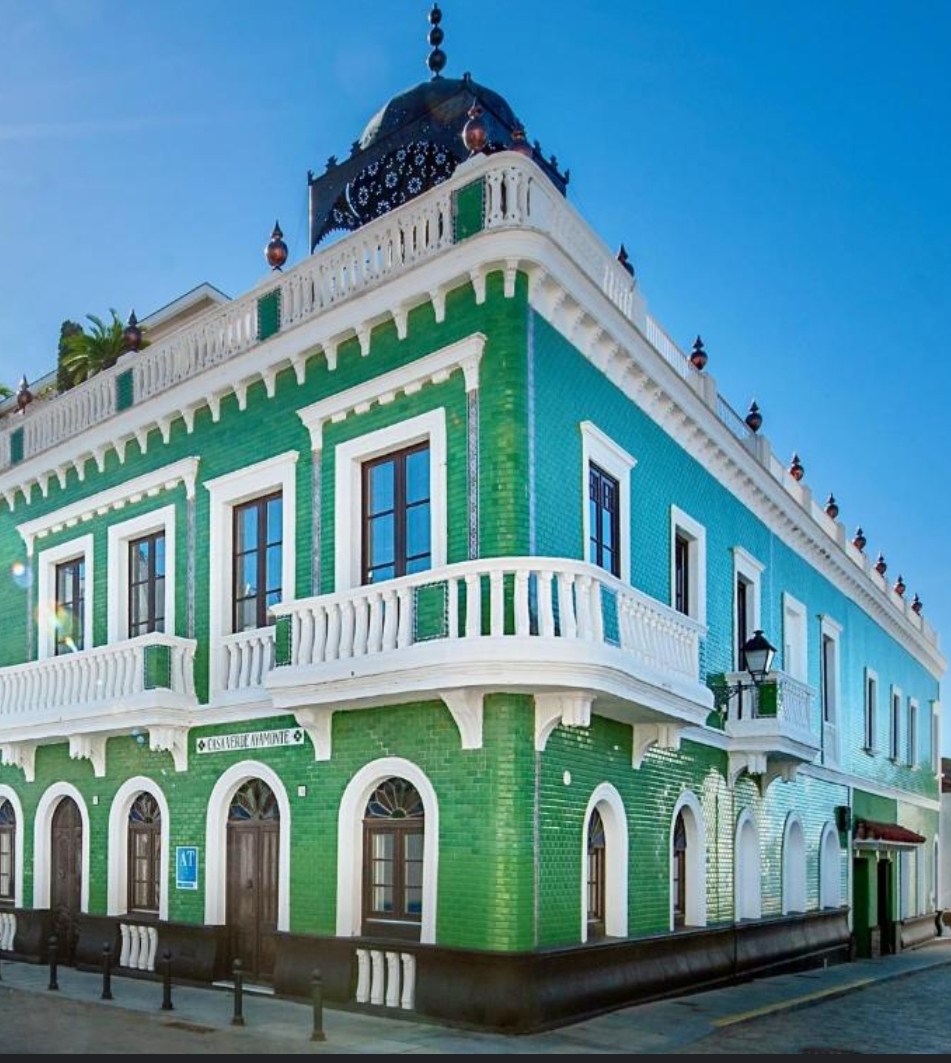 Exterior of Casa Verde Apartments in Ayamonte Spain, a striking green tiled historic building with white balconies and ornate architectural details