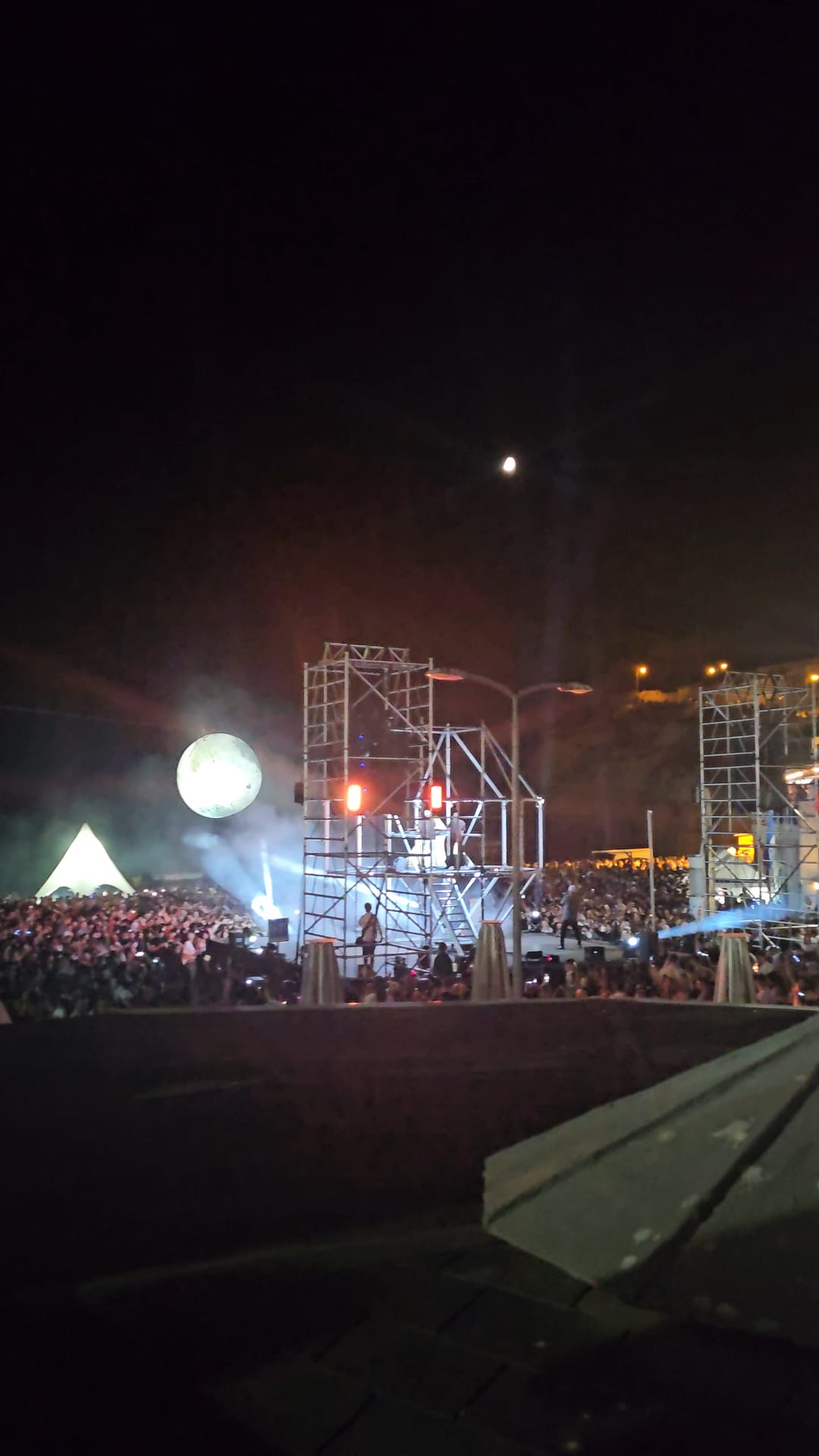 Large crowd gathered on the beach at Carvoeiro Black and White Night festival with lit scaffold stage