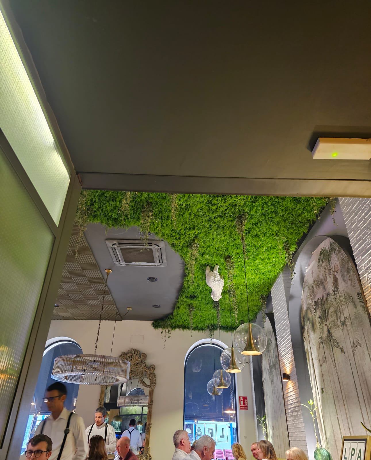 Interior of a restaurant in Ayamonte Spain with a living green moss ceiling and white lamb sculpture
