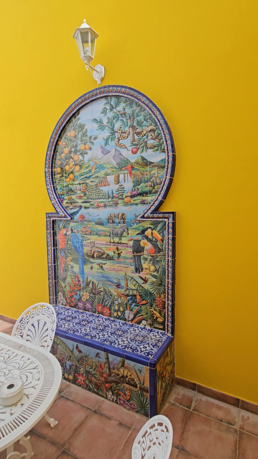 Colorful hand painted ceramic tile mural with tropical wildlife on a bright yellow wall at Casa Verde apartments