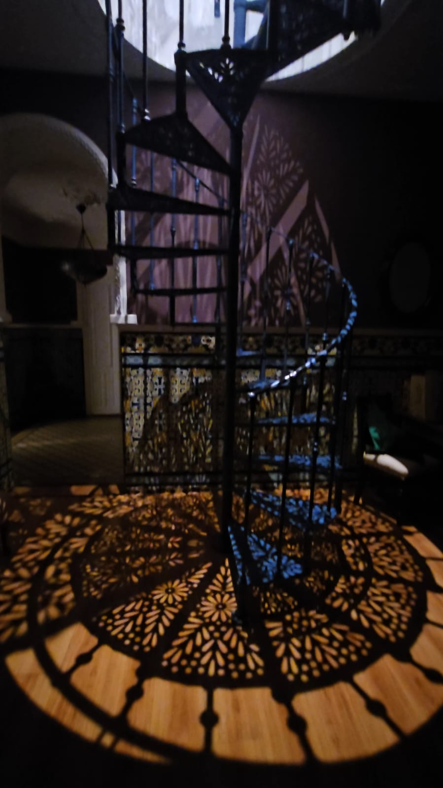 Close up of decorative wrought iron spiral staircase casting ornate shadow patterns on the floor at Casa Verde apartments in Ayamonte