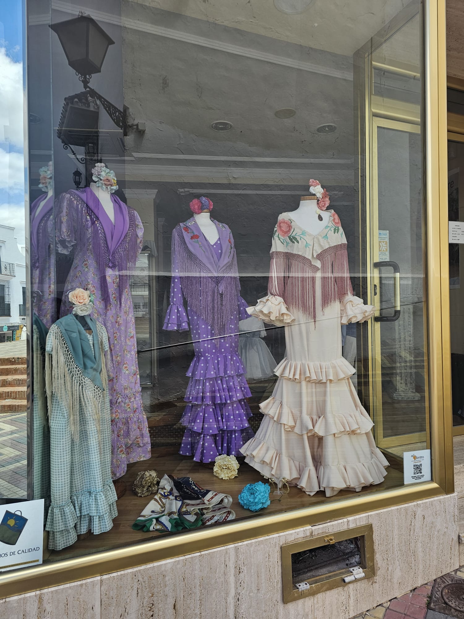 Shop window displaying colorful traditional Spanish flamenco dresses in Ayamonte
