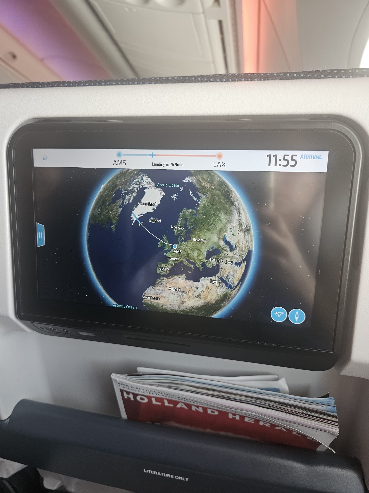 In-flight entertainment screen showing a flight map over the Atlantic Ocean with 11 hours 55 minutes remaining on a flight to LAX