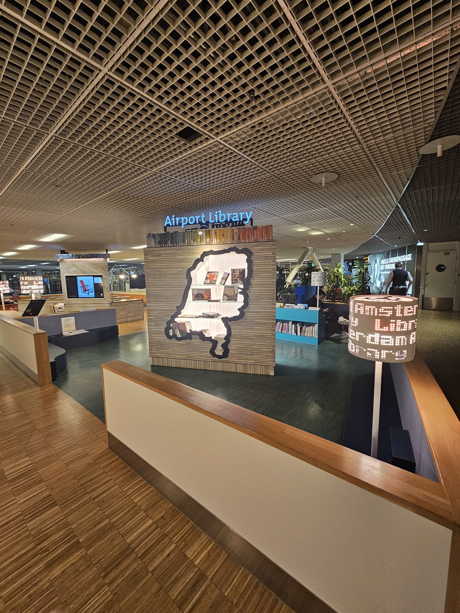 Amsterdam Airport Library with a Netherlands-shaped book display and colorful book shelves inside Schiphol Airport