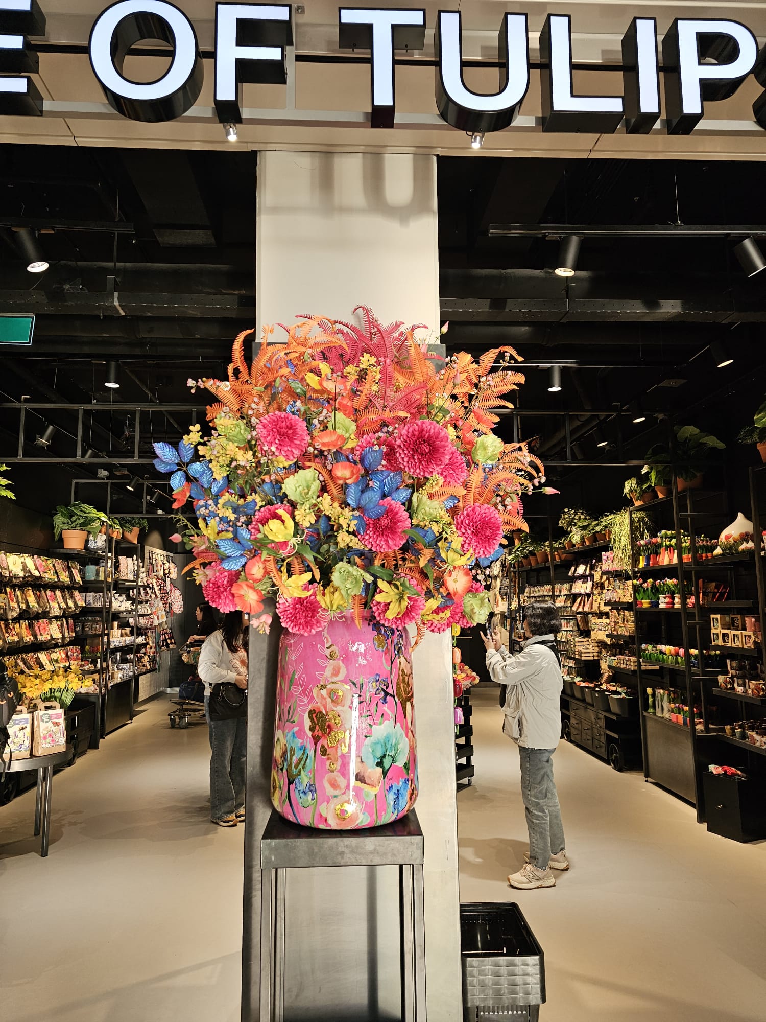 Colorful oversized floral arrangement in a pink vase at the entrance of a tulip gift shop inside Amsterdam Schiphol Airport