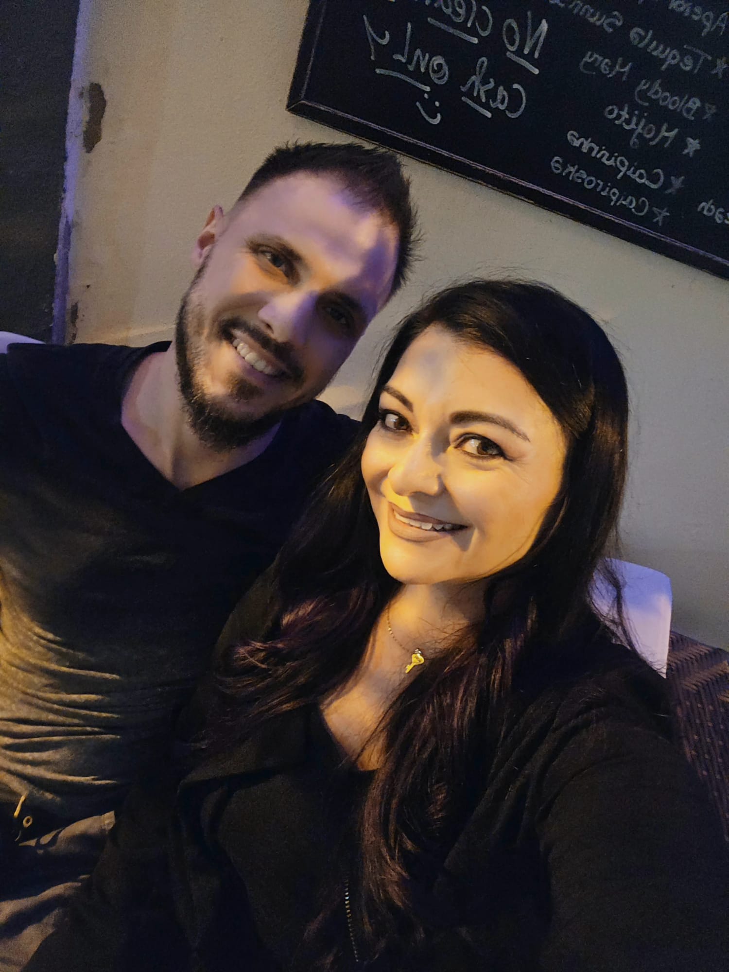 Couple smiling together in a cozy dimly lit bar in Portugal, celebrating two years of living as expats