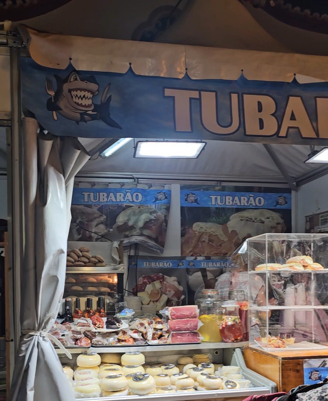 Tubarao cheese vendor stall displaying a colorful variety of Portuguese cheeses at an outdoor fair