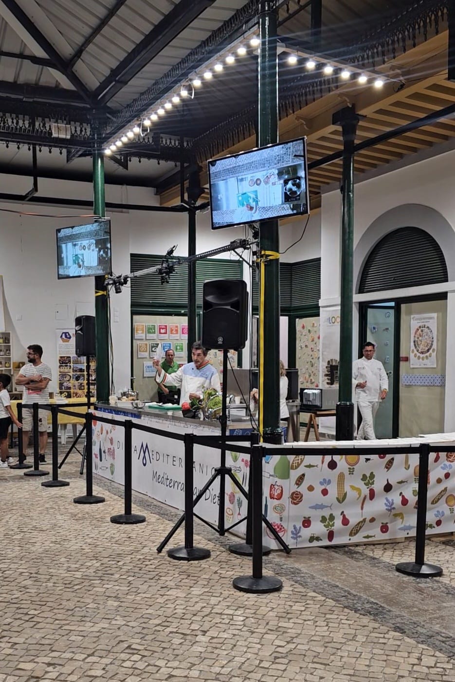 Live cooking demonstration inside a market hall at the Mediterranean Diet Fair in Tavira, Portugal