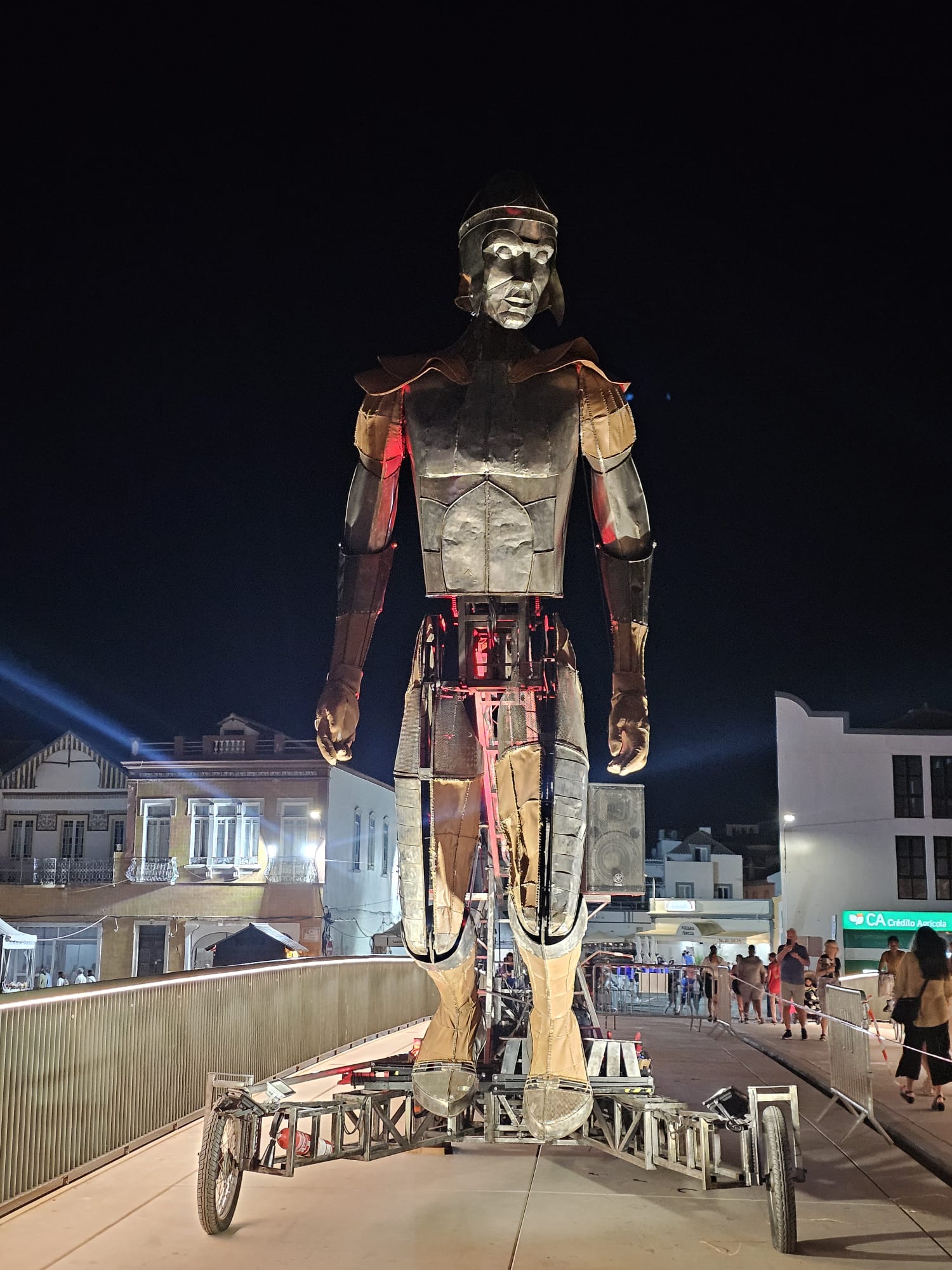 Large mechanical human sculpture walking through the streets of Tavira at night during the Mediterranean Diet Fair