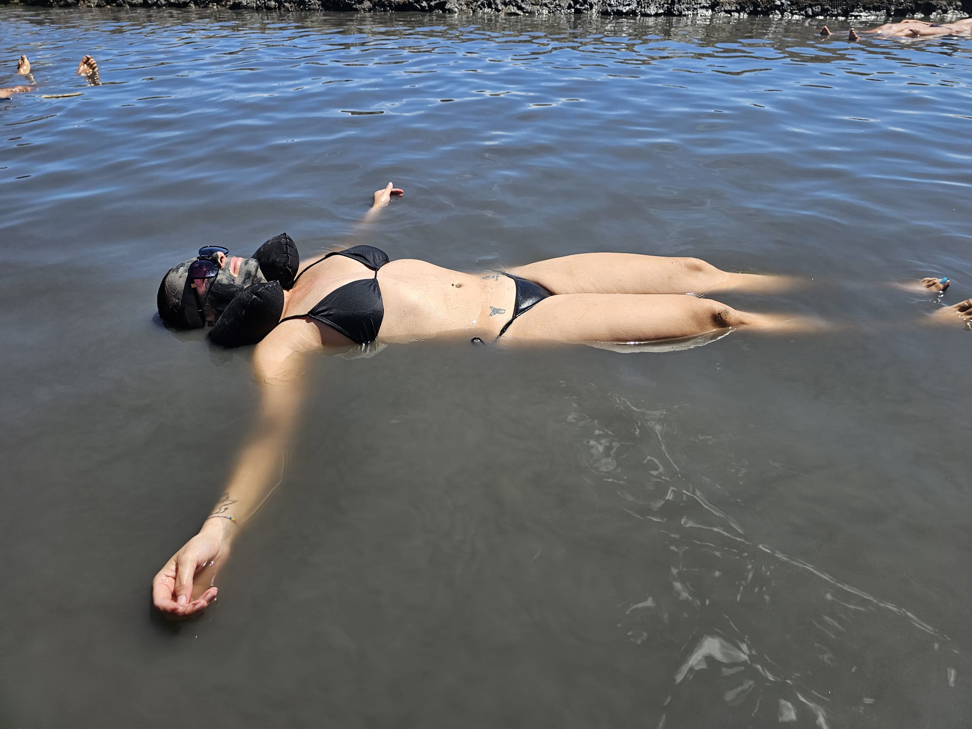 Woman in a black bikini floating effortlessly on her back in a mineral-rich salt flat pool at an Algarve spa in Portugal