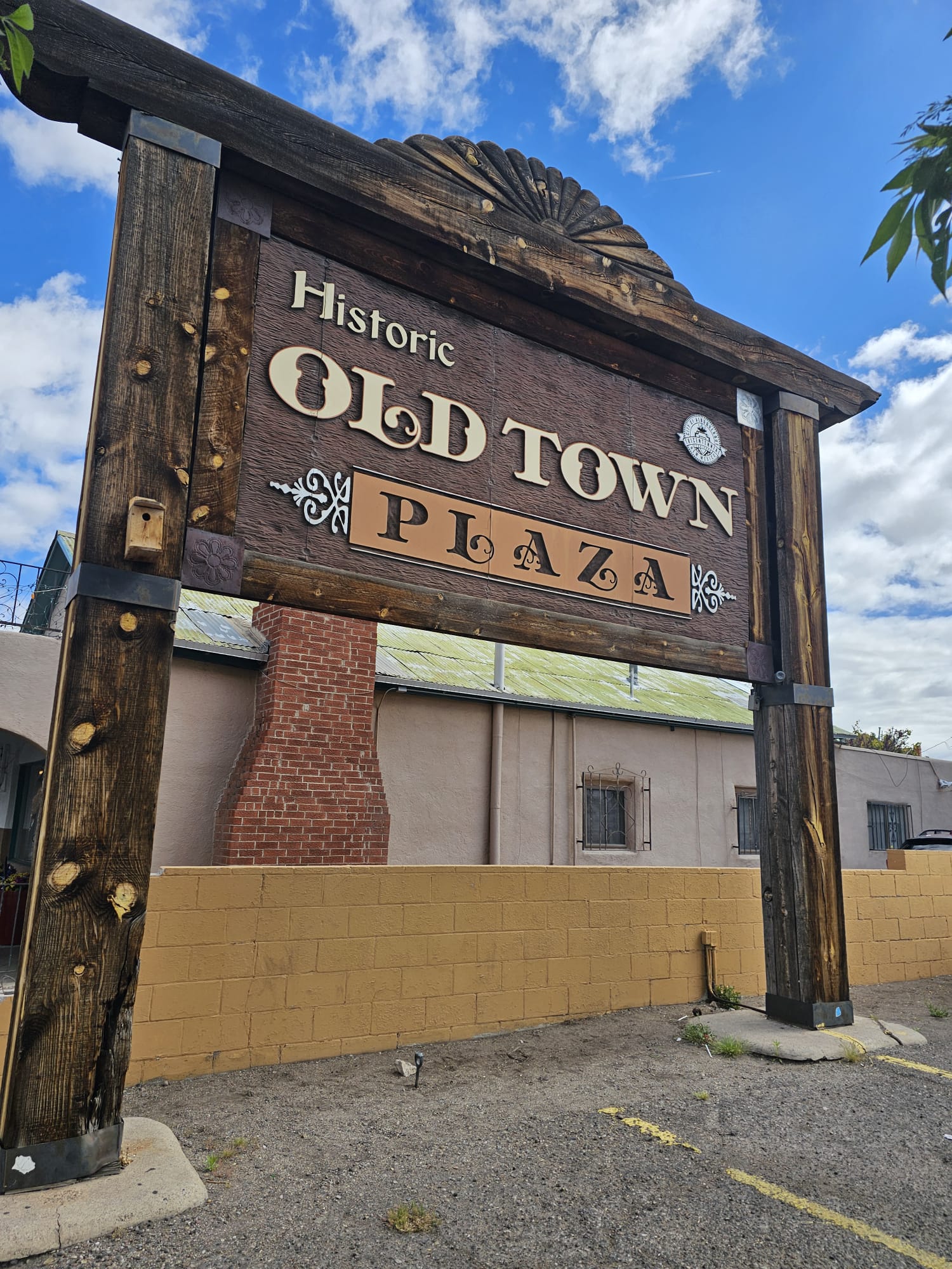 Rustic wooden sign for Historic Old Town Plaza in Albuquerque, New Mexico against a bright blue sky