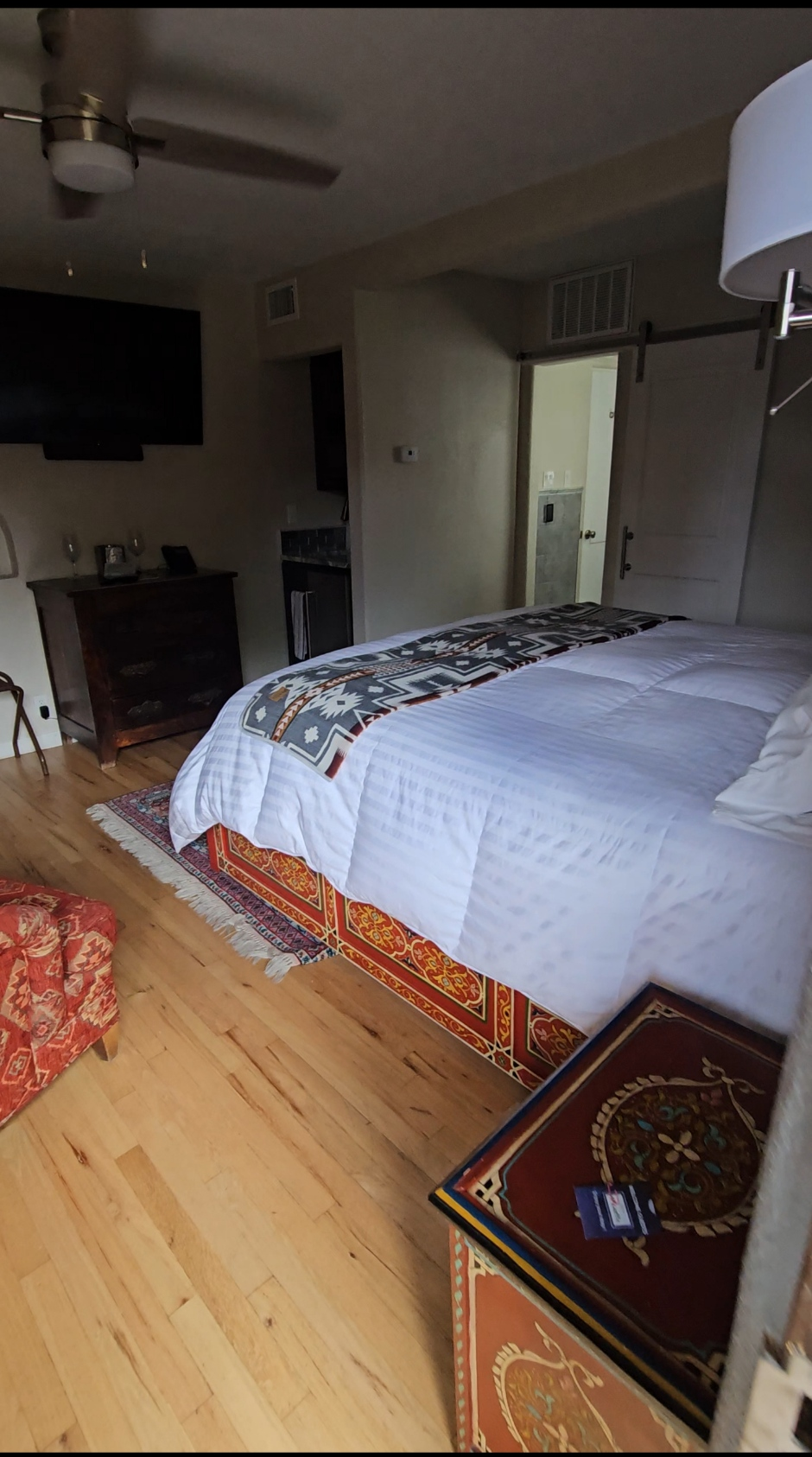 Cozy casita bedroom interior with a king bed featuring a Southwestern patterned runner, hardwood floors, fireplace, and barn door at Casas de Suenos