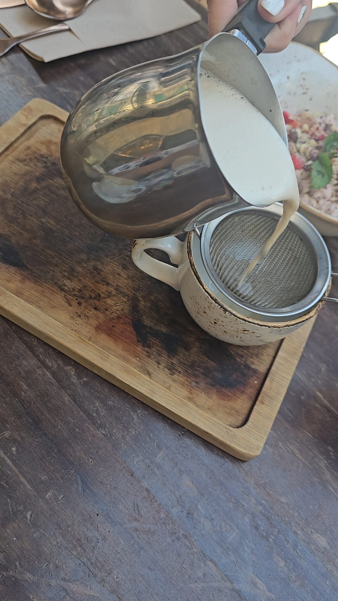 Chai Tea latte being poured through a strainer