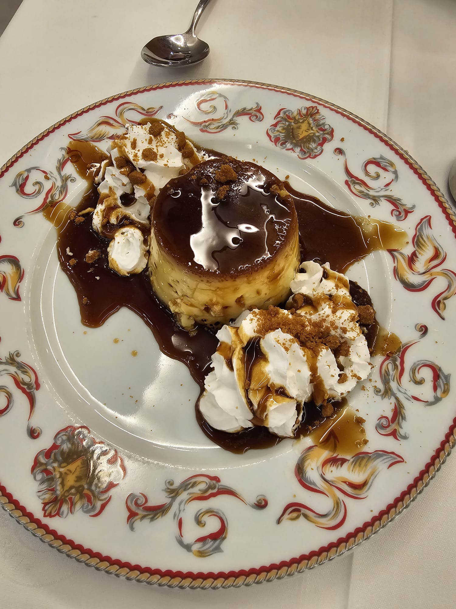dessert plate featuring a caramel-glazed flan with whipped cream.