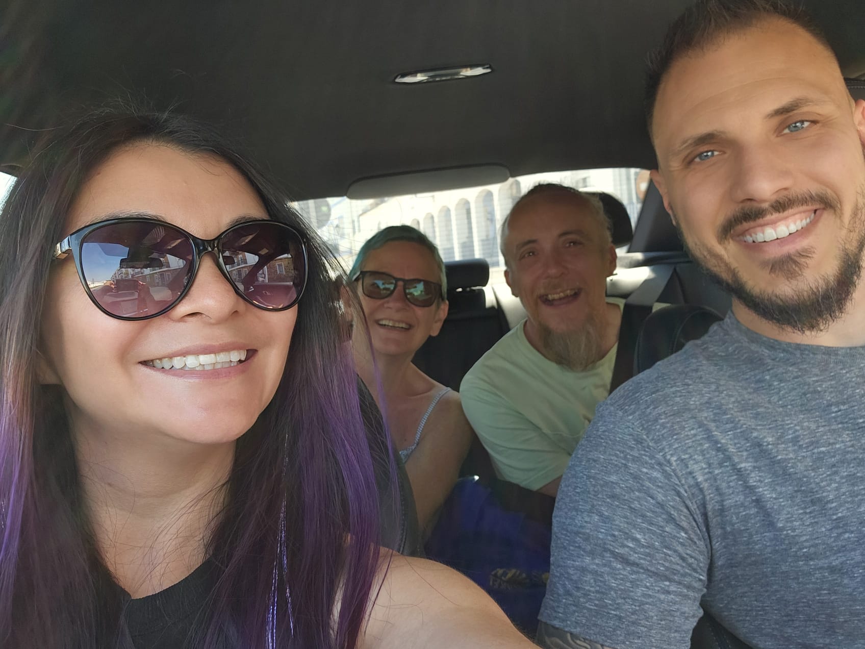 Four friends smiling for a selfie inside a car during a road trip to Málaga, Spain
