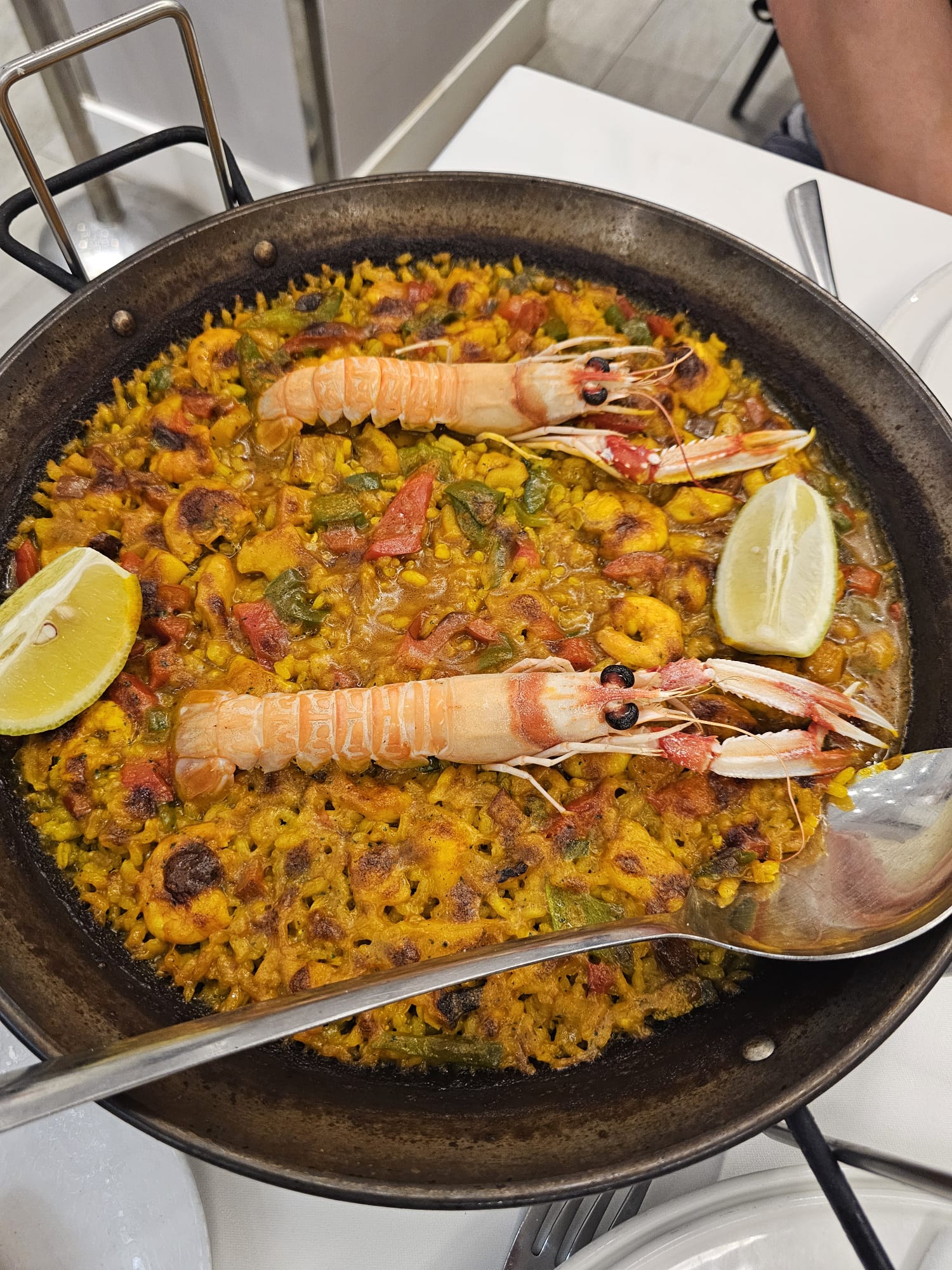a large traditional metal pan of seafood paella with two large langoustines on top