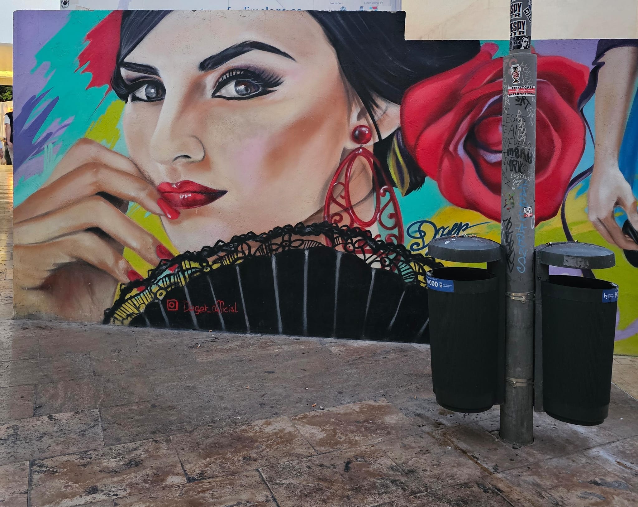 Colorful street mural in Málaga depicting a flamenco woman with dark hair, red rose earrings, red lips, and a black fan