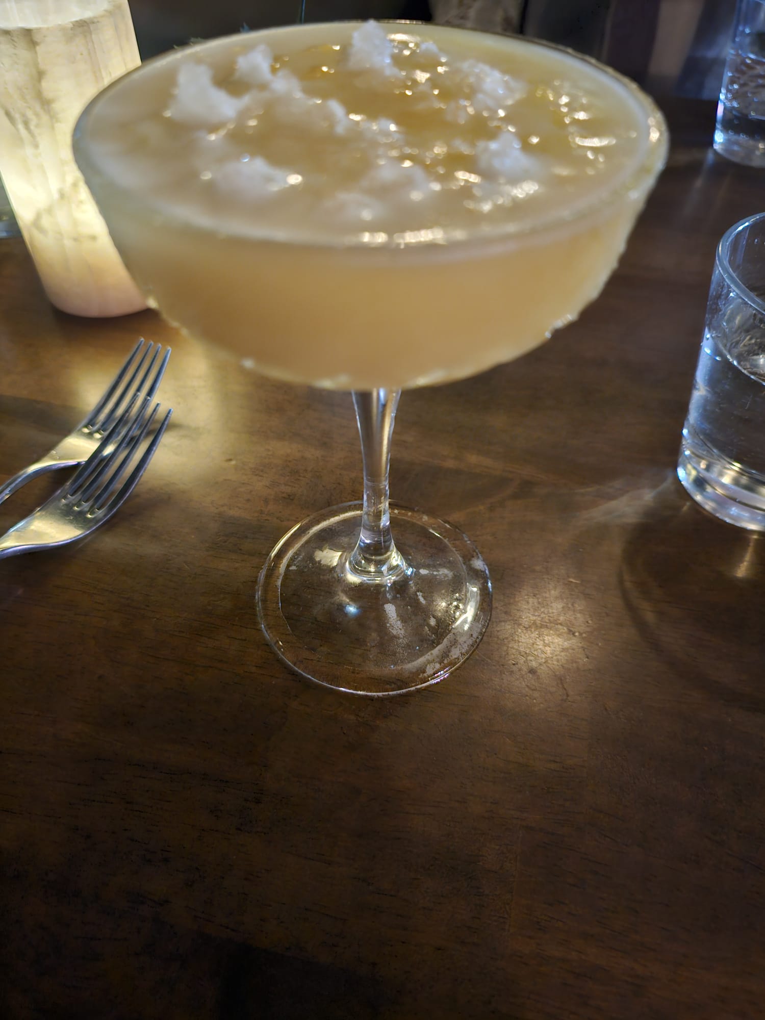 A frothy, pale yellow cocktail served in a coupe glass.