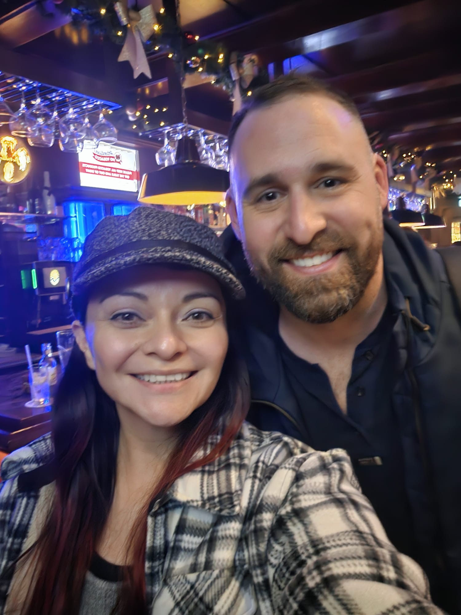 Friends  smiling for a selfie inside a lively bar with colorful neon lighting in Amsterdam