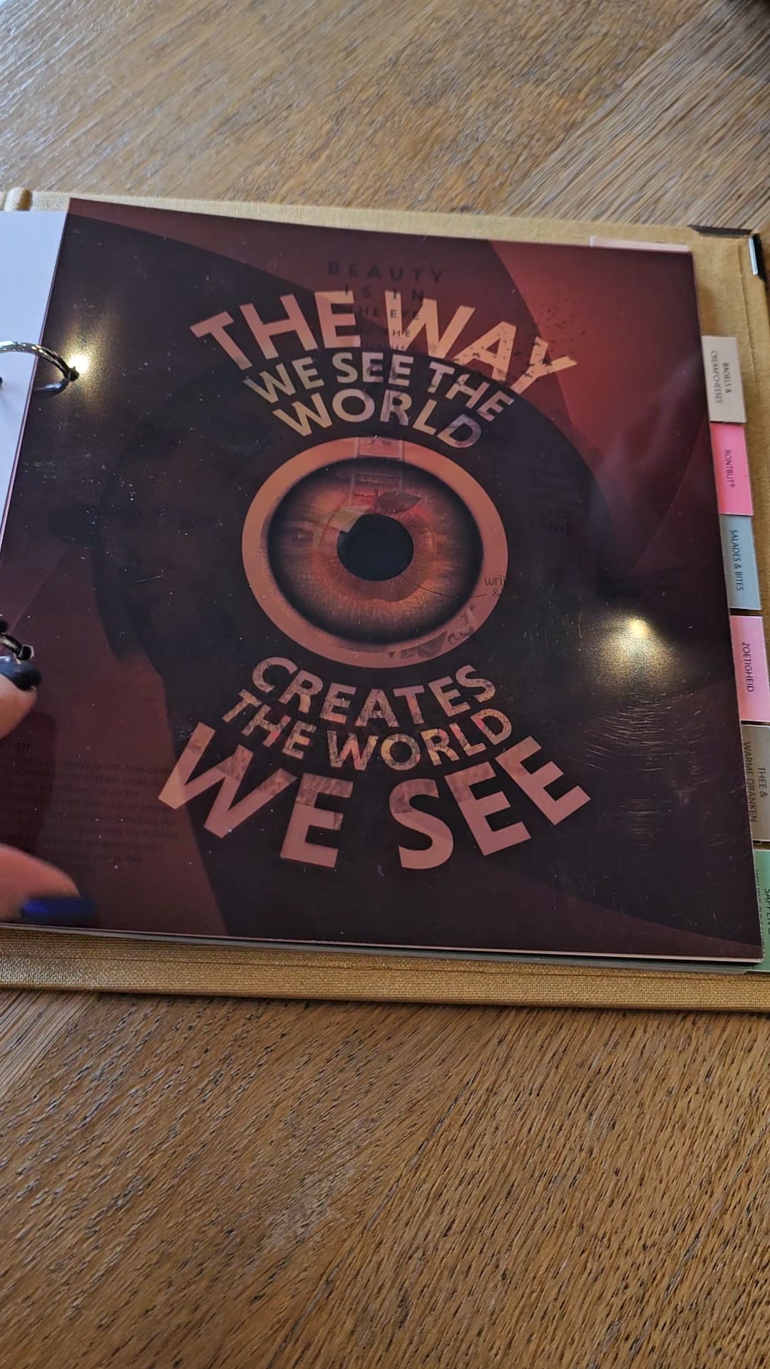 A stylish, dark-themed menu from Bagels and Beans with the quote: "The way we see the world creates the world we see."