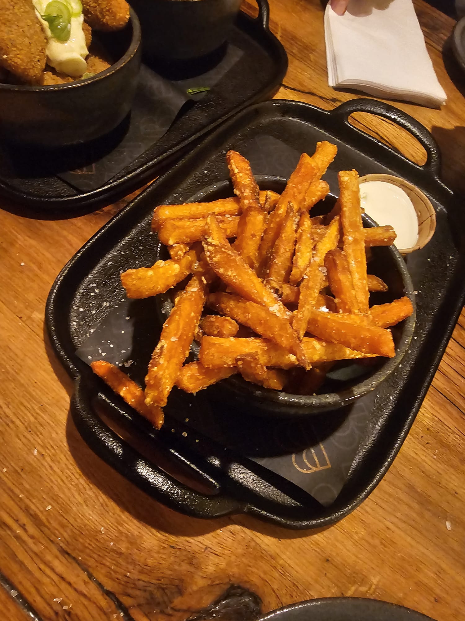A black bowl filled with crispy, thin-cut sweet potato fries